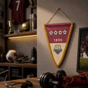 Gagliardetto triangolare bordeaux e crema con palloni da calcio, l'anno 1896 e il logo BC Soccer, appeso a una parete.