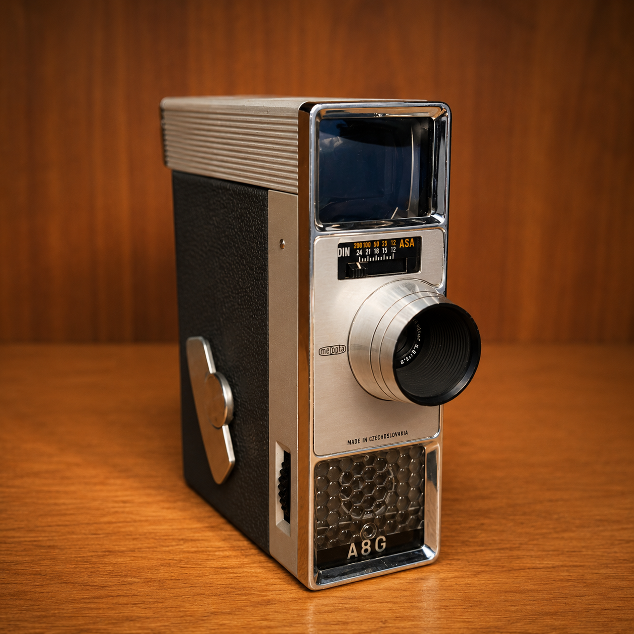 Cinepresa Meopta A8G 8mm vintage, colore argento e nero, su sfondo di legno, ideale come oggetto di scena per produzioni.
