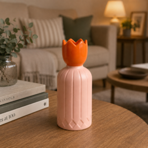 Vaso decorativo bicolore con base rosa a coste e tappo arancione a forma di tulipano, su un tavolino in legno.
