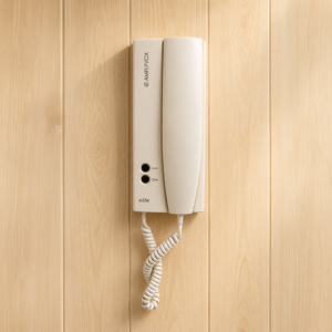 Citofono Amplivox Elite di colore beige montato su una parete a pannelli di legno chiaro, con cornetta e cavo a spirale.