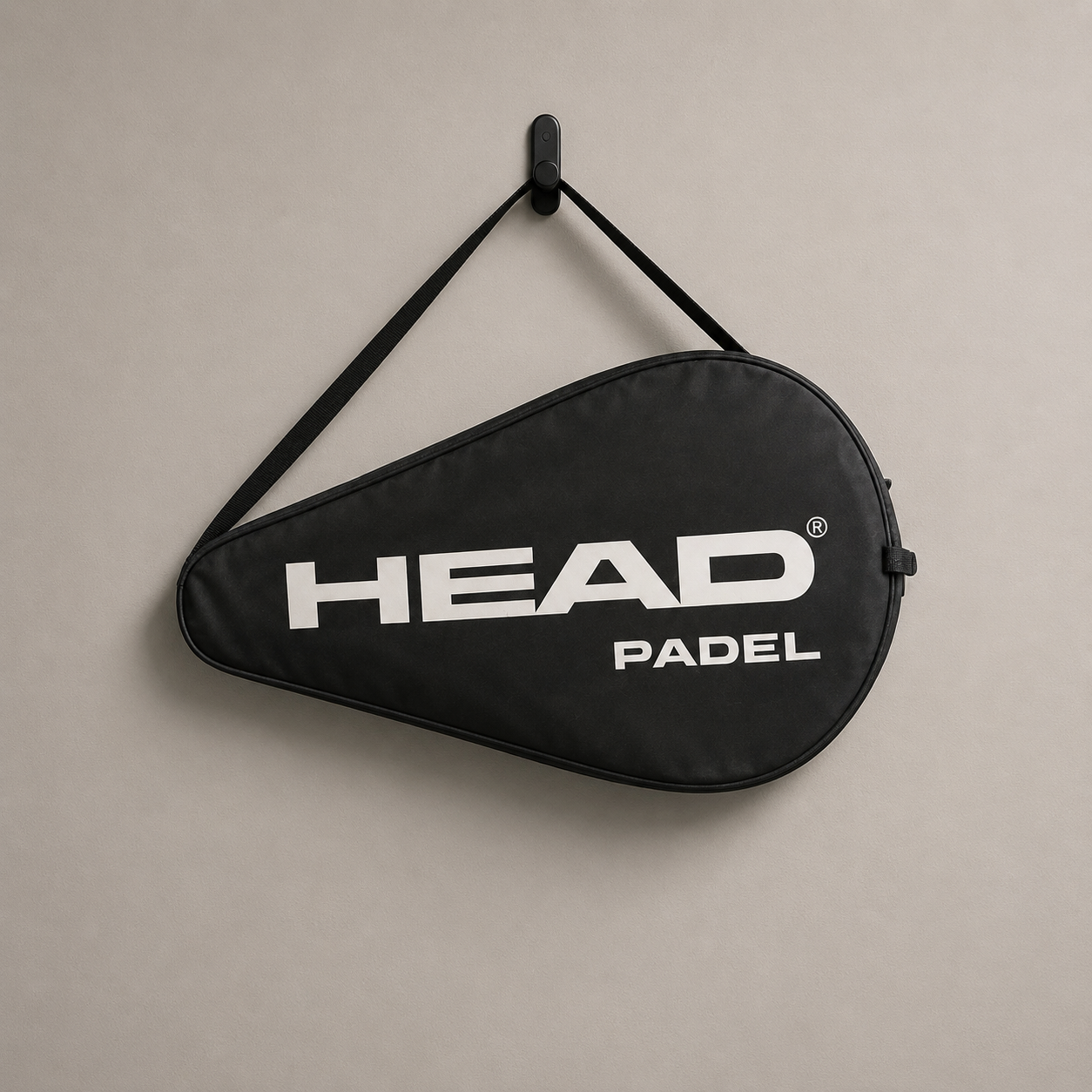 Fodero nero per racchetta da padel HEAD PADEL appeso a un gancio nero su una parete grigia chiara.