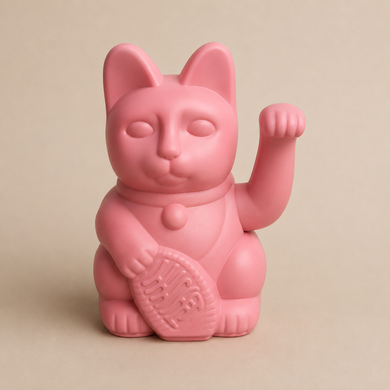 Statuetta di Maneki-neko rosa opaco con zampa alzata e moneta, su sfondo neutro.