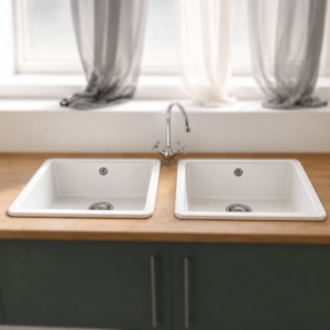 Lavello da cucina doppio in composito bianco con rubinetto cromato classico, incassato in un piano di lavoro in legno chiaro sopra un mobile grigio scuro.