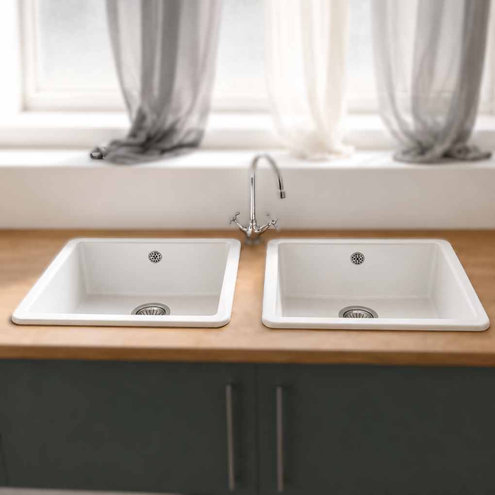 Lavello da cucina doppio in composito bianco con rubinetto cromato classico, incassato in un piano di lavoro in legno chiaro sopra un mobile grigio scuro.