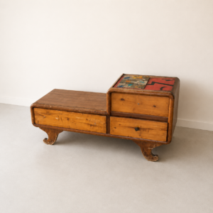Mobile basso asimmetrico in legno chiaro con quattro cassetti, bordi arrotondati e piano superiore decorato con motivi astratti colorati.