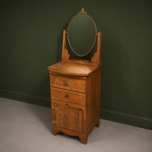Toeletta in legno massello con due cassetti, anta intagliata a girasole e specchio ovale orientabile su sfondo verde scuro.