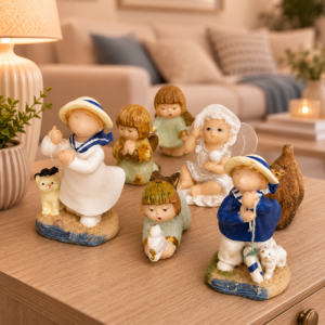 Collezione di sette statuette in resina raffiguranti bambini e angeli in diverse pose e abiti, su un tavolo di legno.
