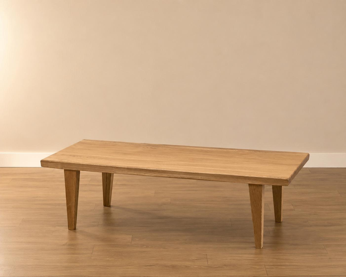 Tavolino basso rettangolare in legno massello chiaro con gambe affusolate, posizionato su pavimento in parquet davanti a una parete beige.