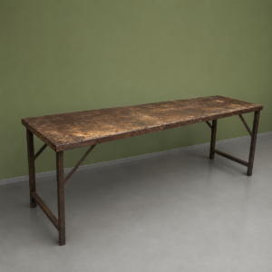 Lungo tavolo industriale vintage con piano in legno scuro e vissuto e struttura in metallo, su sfondo verde e pavimento grigio.
