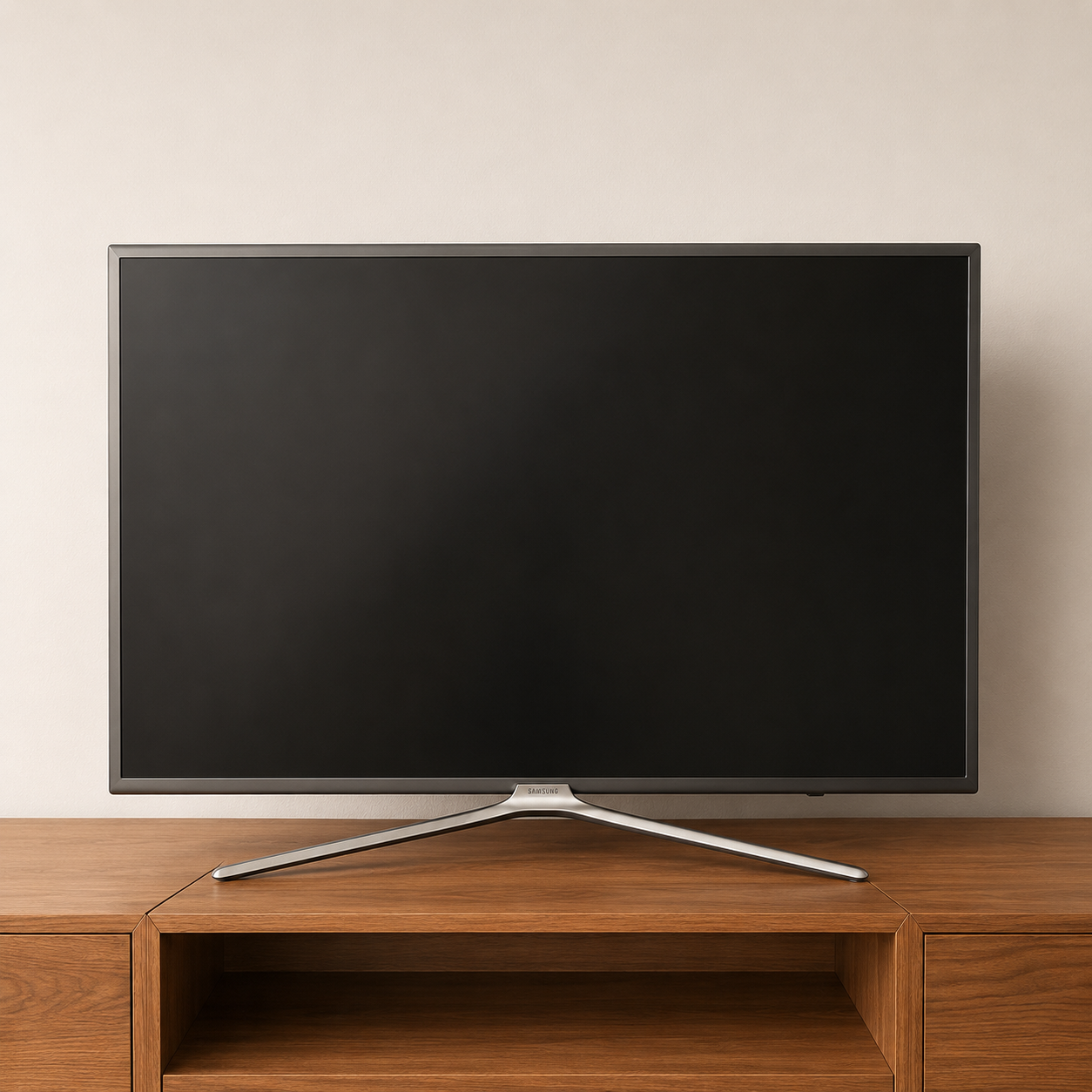 Smart TV Samsung 4K con cornice sottile e stand argentato, posizionata su un mobile in legno chiaro davanti a una parete beige.
