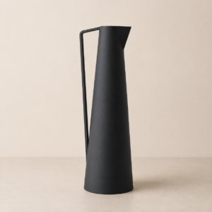Caraffa conica alta e sottile di colore nero opaco, con manico angolare integrato, su sfondo neutro beige.